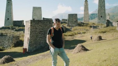 Dağlardaki eski harabelerin yanında duran bir gezgin. Sırt çantalı genç turistin yan görüntüsü