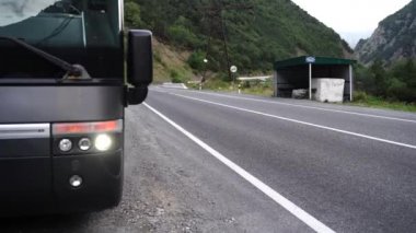 Dağlık alanda yanıp sönen park ışıkları olan bozuk otobüsü kaldırıma kapatın. Bulutlu havada yolun yakınına park edilmiş büyük bir araç. Acil durum kavramı.