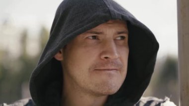 Kapüşonlu genç adam dudaklarını ısırıyor. 