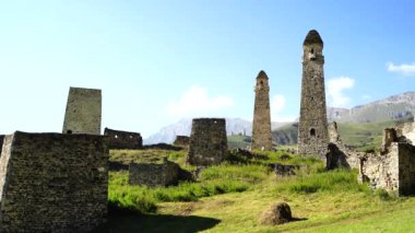 Yeşil dağlık arazide eski taş kuleler. Yeşil tepenin üzerindeki antik taş binalar yaz günü orman ve sisle kaplı dağlara karşı..