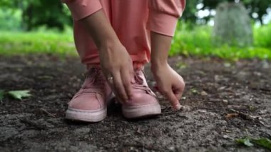 Ayakkabılarını temizleyen kadına yaklaş. Pembe spor ayakkabılı kadın yazın parkta durur.