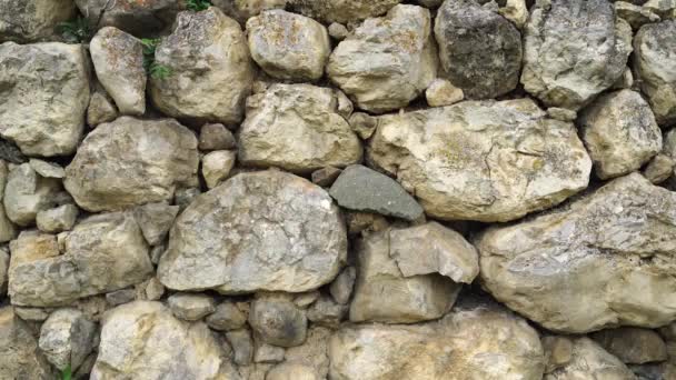 縫い目と様々な形の古い石のテクスチャ みすぼらしい石積みを閉じてください 不均一な古代の壊れやすい石畳から石の壁 — ストック動画