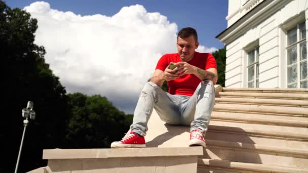 Joven Hombre Guapo Sentado Las Escaleras Frente Del Edificio Utilizando — Vídeos de Stock