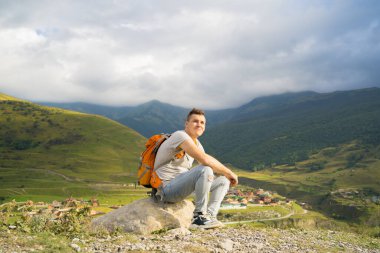 Yorgun bir seyyah tepede dinleniyor. Dağlarda aktif bir yürüyüşten sonra taşın üzerinde oturan bitkin erkek turist.