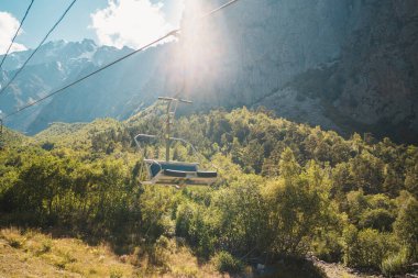 Dağlık bir bölgede ağaçların yanındaki teleferik. Modern teleferik muhteşem bir dağlık alanda bulunuyor..