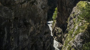 Dağ nehri yazın kayaların arasından akar. Güneşli bir günde geçitten geçen hızlı su.