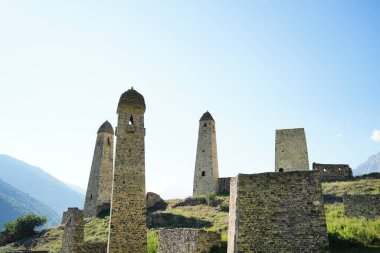 Yeşil dağlık arazide eski taş kuleler. Yeşil tepenin üzerindeki antik taş binalar yaz günü orman ve sisle kaplı dağlara karşı..
