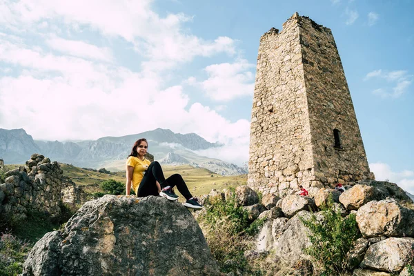 Mujer Joven Sienta Piedra Cerca Viejas Torres Fondo Poderosas Montañas — Foto de Stock