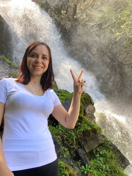 一个年轻女子在瀑布背景下远眺的画像 山区欣赏美丽风景的成年女性游客 — 图库照片