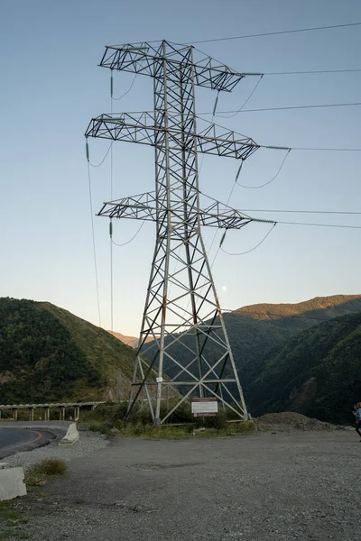 High voltage electric transmission tower in mountainous area. Object of electric power line in mountains in evening