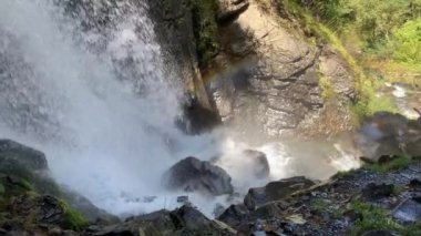 Dağ nehri taştan kıyıya doğru akıyor. Temiz su yolu güneşli havada taşların üzerinden akar..