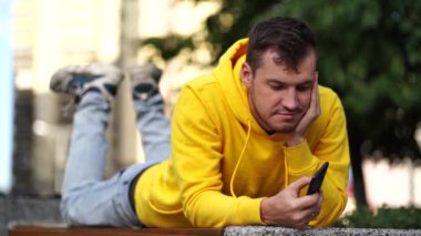 Elinde telefon olan genç bir adam. Bir apartmanın avlusunda akıllı telefon kullanan bir adam..