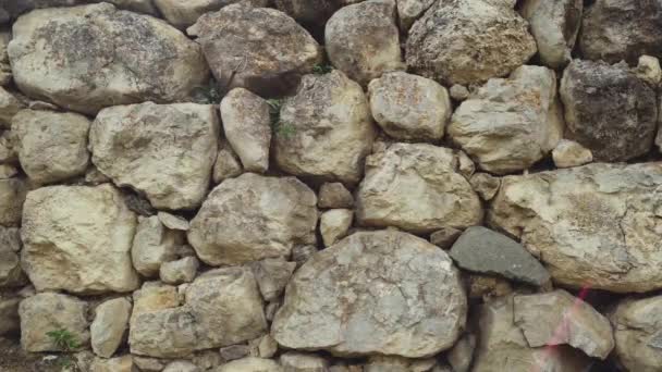 用接缝制成的各种形状的旧石头的结构 接近破旧的砖石结构 不同古老易碎鹅卵石的石墙 — 图库视频影像