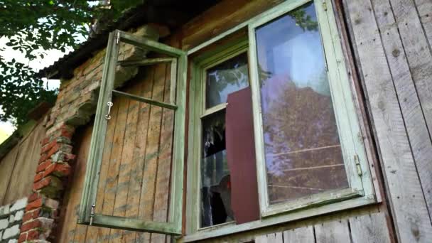 Raam met gebroken glas in oud gebouw. Houten raamkozijn met gedeeltelijk gebroken glas in oud verlaten houten gebouw. — Stockvideo