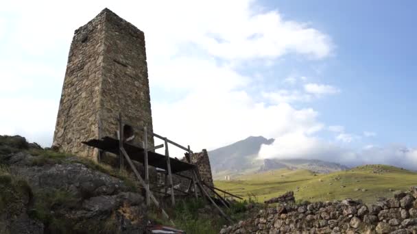 Oude stenen toren in groen bergachtig terrein. Oude stenen gebouw van de oude stad gelegen op een groene heuvel tegen bergen bedekt met bos en mist in de zomerdag — Stockvideo