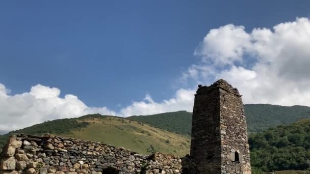 Vecchia torre in pietra nel verde terreno montagnoso. Antica costruzione in pietra del centro storico situato sulla collina verde contro le montagne coperte di foresta e nebbia nella giornata estiva — Video Stock