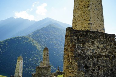 Yeşil dağlık arazide eski taş kuleler. Yeşil tepenin üzerindeki antik taş binalar yaz günü orman ve sisle kaplı dağlara karşı..