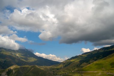 Dağ zirveleri bulutlu gökyüzüne karşı. Parlak bulutlu gökyüzüne bakan muhteşem kayalıklardan oluşan tepeler.