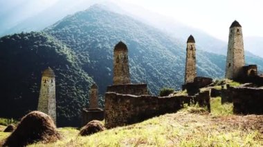 Yeşil dağlık arazide eski taş kuleler. Eski şehrin antik taş binaları dağlara karşı yeşil tepenin üzerinde yer alır.