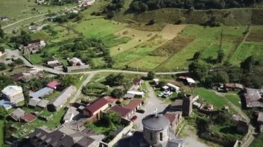 Yeşil dağlık arazide eski taş kuleler. Eski şehrin antik taş binaları dağlara karşı yeşil tepenin üzerinde yer alır.