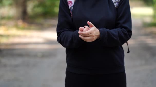 Oigenkännlig kvinna knådar händerna på gatan. Närbild av knådning av kvinnor händer utomhus — Stockvideo