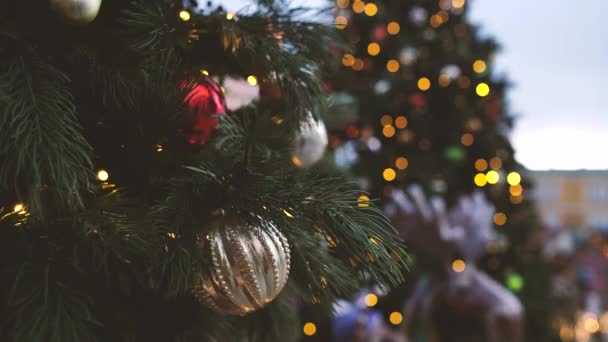 靠近圣诞树的一部分 有不同的圣诞节玩具和花环在街上的傍晚城市 有装饰性装饰的针叶树 营造节日气氛 — 图库视频影像