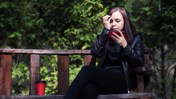 Ung Kvinna Skinnjacka Sitter Bänken Och Spelar Smartphone Parken Vuxen — Stockvideo