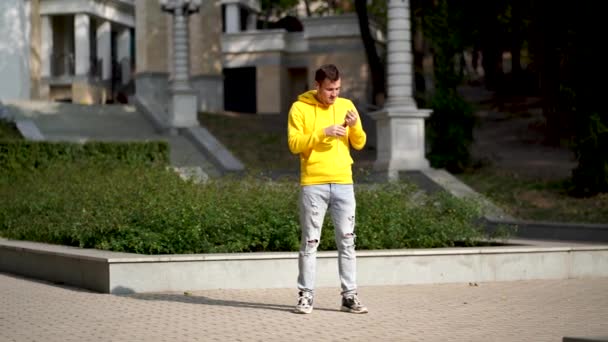 Sarı Kapüşonlu Genç Adam Binanın Önünde Kulaklıkla Müzik Dinliyor Dans — Stok video