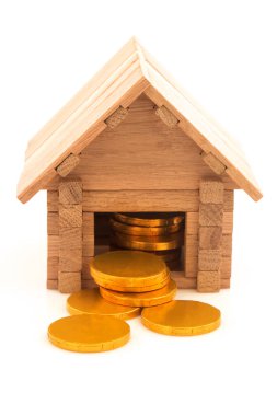 Beyaz arka planda izole edilmiş çikolatalı altın sikkeleri olan tahta oyuncak ev..