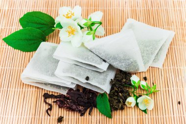 Çay poşetleri ve taze çiçek ahşap paspasın üstünde doğal bir konsept.