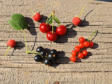 Kuş üzümü siyah ve kırmızı, kiraz, ahududu Olgun, taze, doğal, gerçek, çeşitli, eski bir ahşap panosuna.