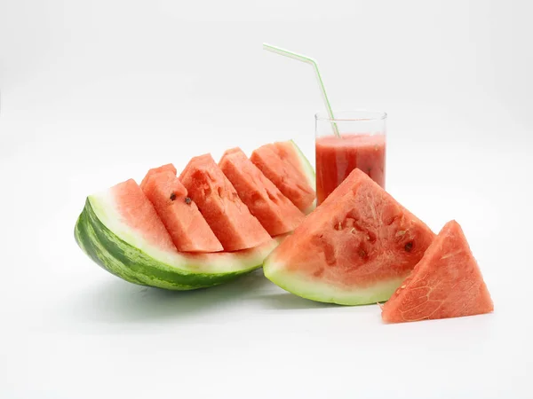 Watermelon slices and a glass of watermelon juice with a straw.