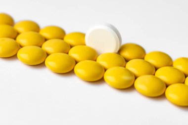 Tabletler sarı ve ortada beyaz bir tablet var..