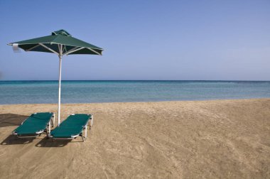 Şemsiye ve plaj sandalye turkuaz deniz kenarında