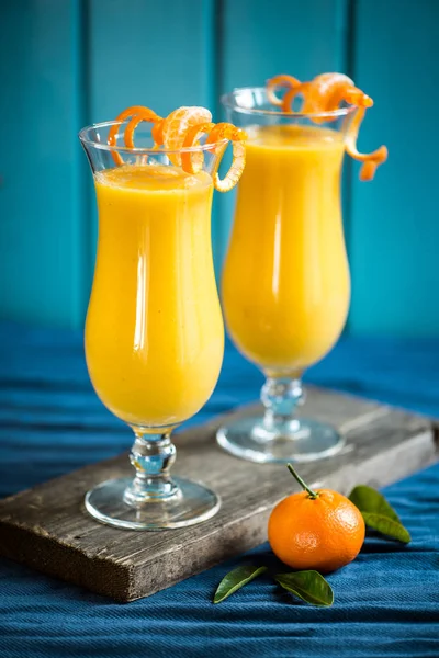 A smoothie with mango, banana and orange decorated with mandarins