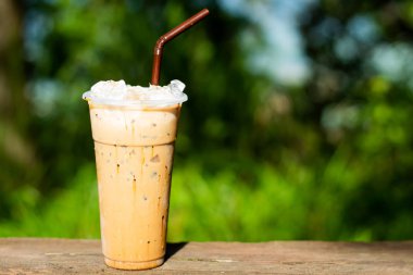 Buzlu kahve ve yeşil ağaçlar bir arka plan.