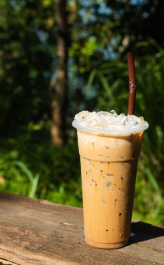 Buzlu kahve ve yeşil ağaçlar bir arka plan.