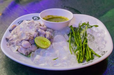 Taze istiridye beyaz bir tabakta sebze ve sos ile.