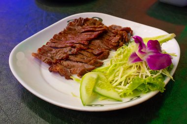 Sebze ve sos ile beyaz bir plaka üzerinde ızgara sığır eti.