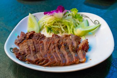 Sebze ve sos ile beyaz bir plaka üzerinde ızgara sığır eti.