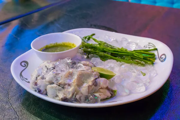 Taze istiridye beyaz bir tabakta sebze ve sos ile.