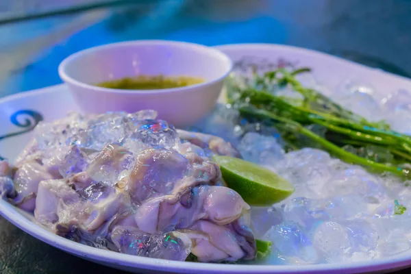 Taze istiridye beyaz bir tabakta sebze ve sos ile.