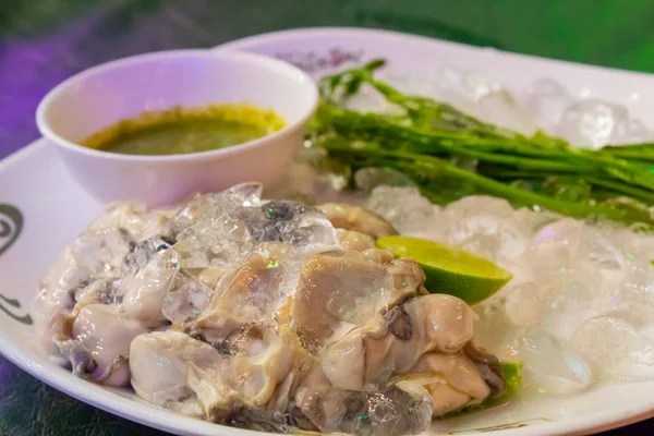 Taze istiridye beyaz bir tabakta sebze ve sos ile.