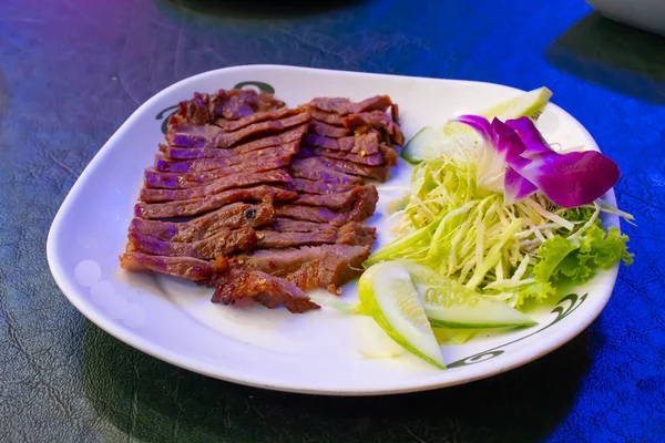 Sebze ve sos ile beyaz bir plaka üzerinde ızgara sığır eti.