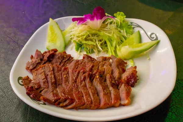 Sebze ve sos ile beyaz bir plaka üzerinde ızgara sığır eti.