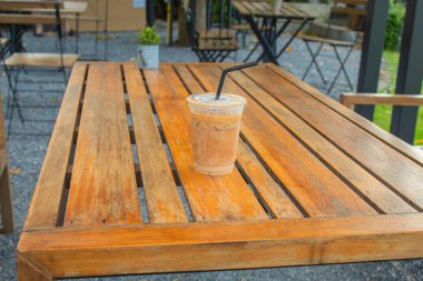 Bahçedeki ahşap bir masa üzerinde buzlu kahve.