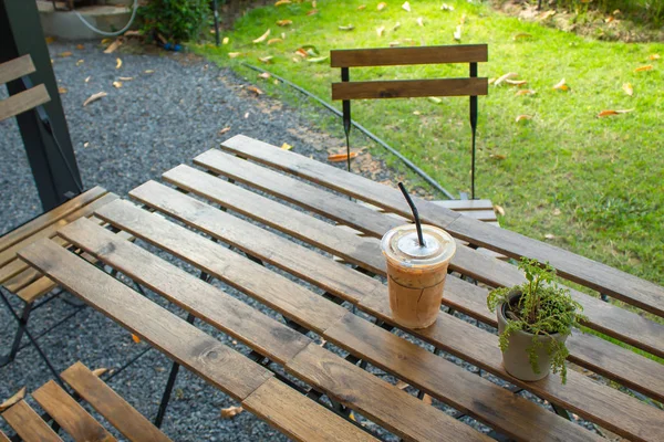 Bahçedeki ahşap bir masa üzerinde buzlu kahve.