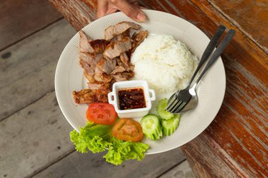 Pirinç, beyaz bir tabakta sebze soslu kızarmış domuz eti.