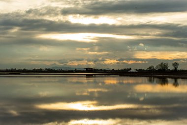 Su yüzeyinden günbatımı ışığı yansıtır.