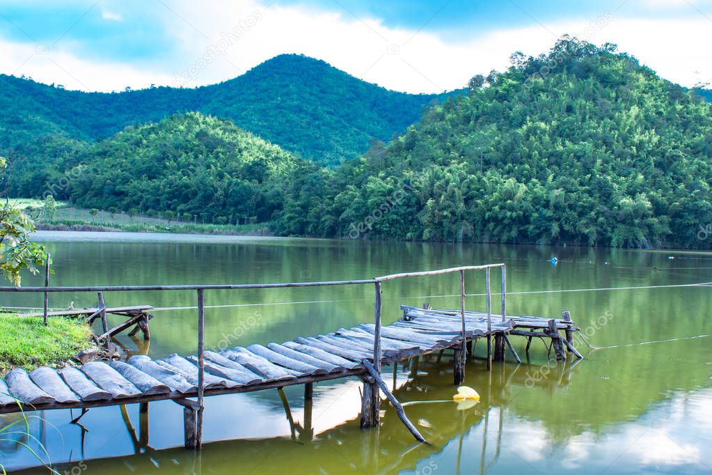 The wooden bridge in the reservoir The background of mountains and trees